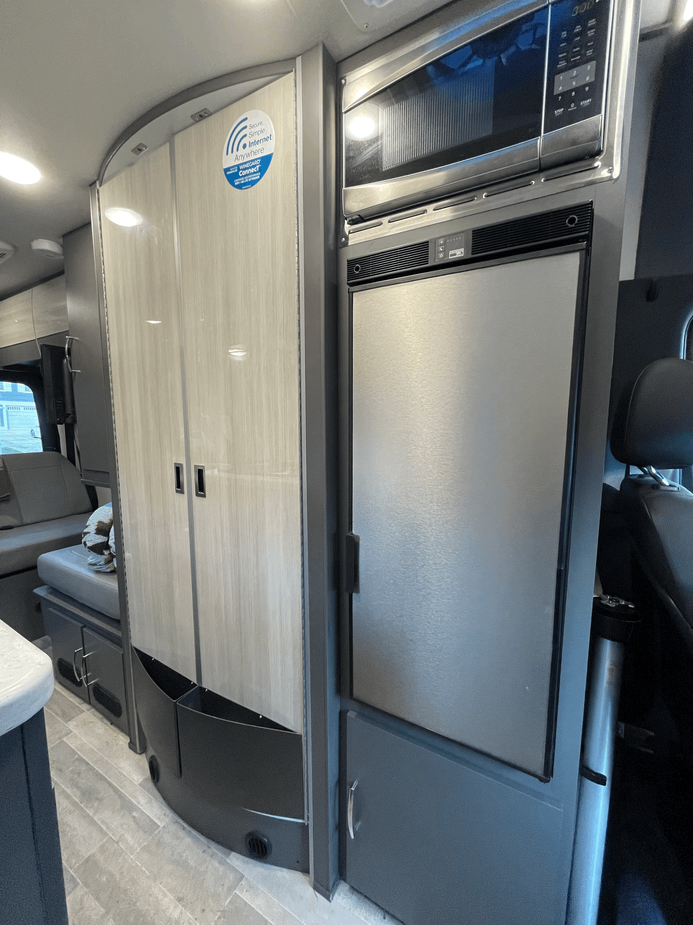 Tour this RV rental's modern interior: sleek microwave, fridge, and spacious light-wood storage for comfortable travel.