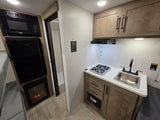 RV rental interior: Kitchen with stove, sink, microwave, fridge, and cozy electric fireplace.