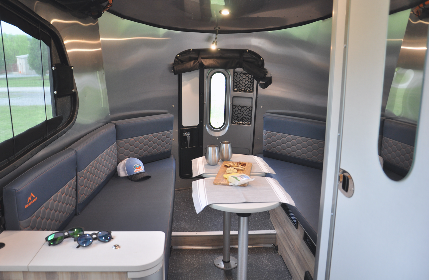 Cozy RV rental interior: A compact dinette area with gray seating, a table with snacks, and modern metallic walls.