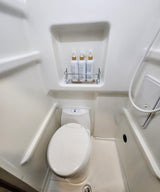 Clean, compact RV rental wet bath featuring a toilet, shower, and labeled toiletries for convenience.