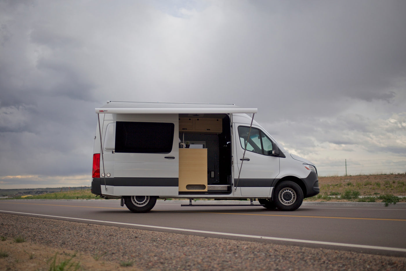 and extended awning on a road. Ready for adventure!|White RV rental conversion van with an open side door — photo 3