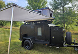 Black off-road camper trailer with awning & rooftop tent, perfect for your next RV rental adventure.