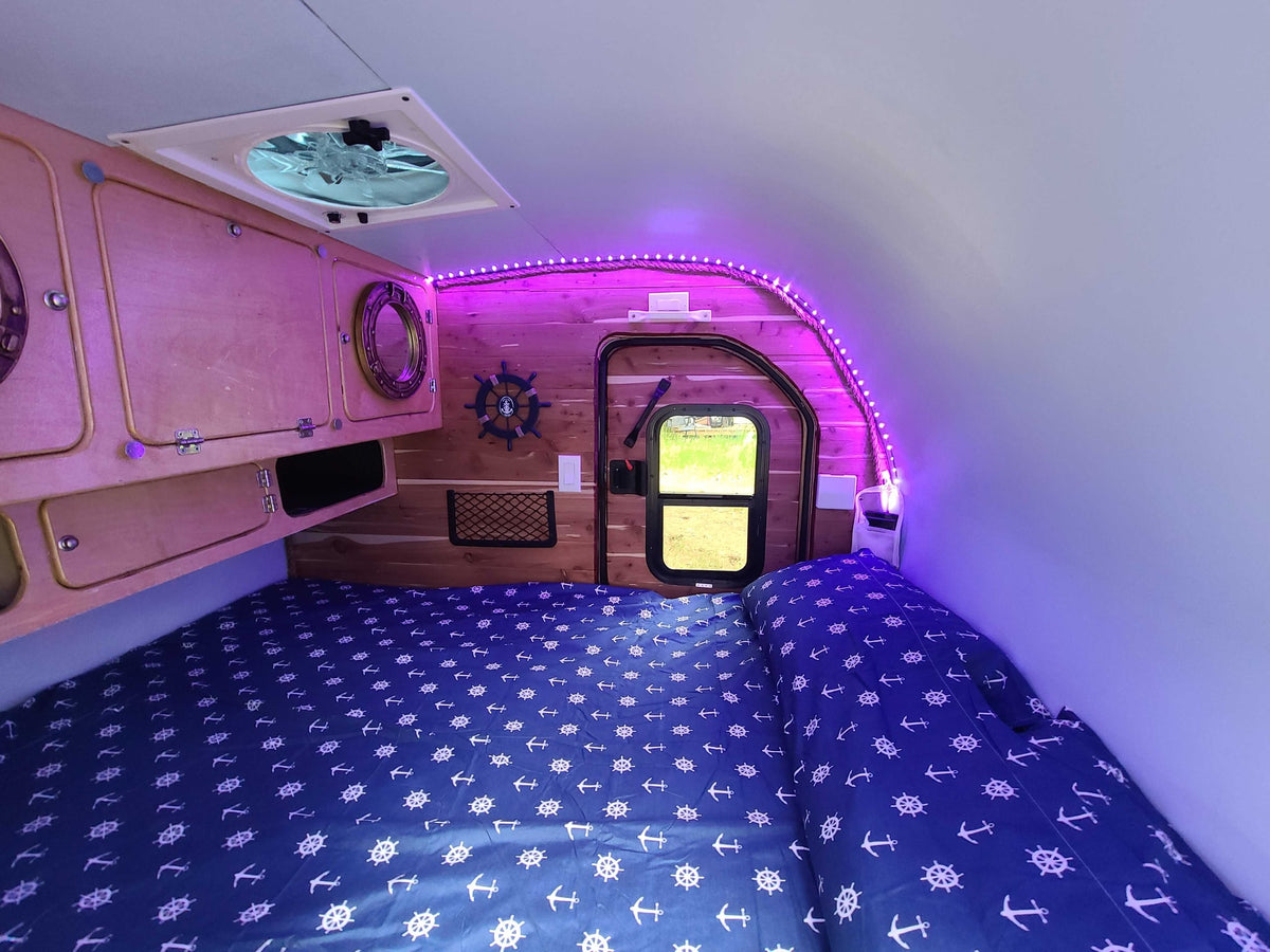 Cozy RV rental interior with nautical bedding, wood accents, and ambient purple LED lighting. — photo 20