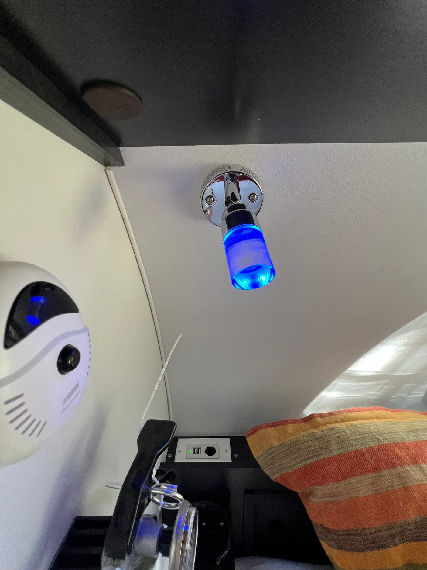 Cozy RV rental interior with blue LED light, air purifier, USB outlets, and a striped pillow, enhancing mobile living comfort.
