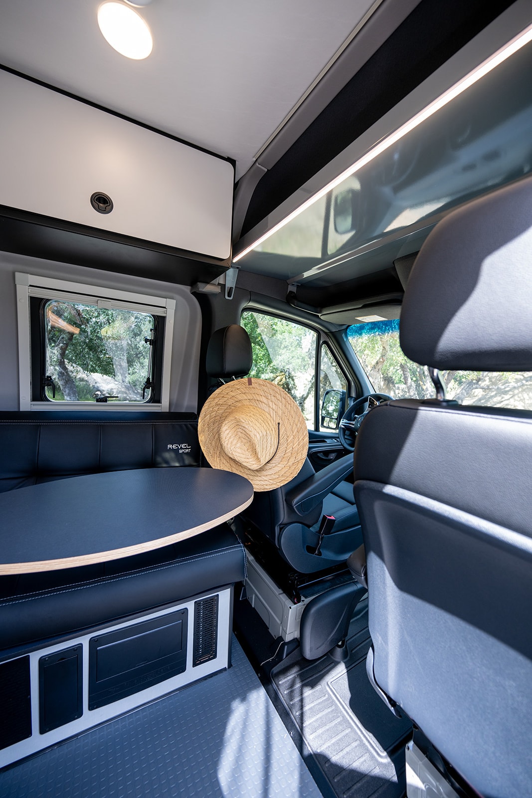 Spacious RV rental interior: modern seating, table, overhead storage, & a view outside. Ideal for travel. — photo 12