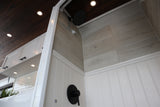 Stylish RV rental interior showcasing a modern shower with grey wood-look tiles, black fixtures, and a warm wood plank ceiling.