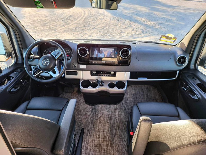 Detailed RV rental interior: Mercedes-Benz cockpit with dashboard, dual seats, and a snowy/sandy view out the windshield. — photo 9