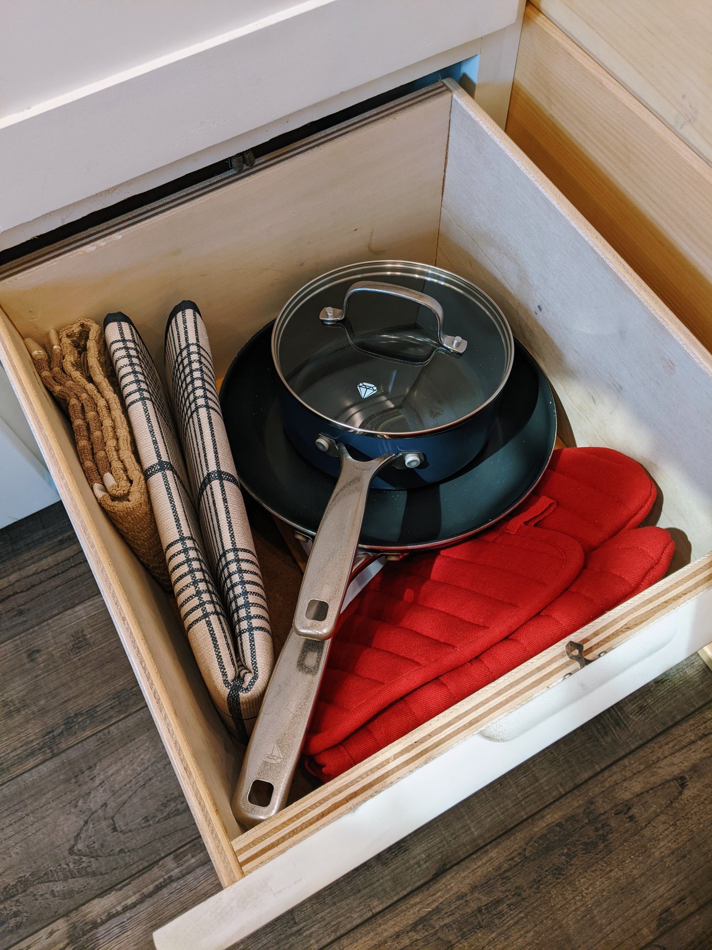Organized RV kitchen drawer with cookware, towels, and oven mitts for easy access in your RV rental.