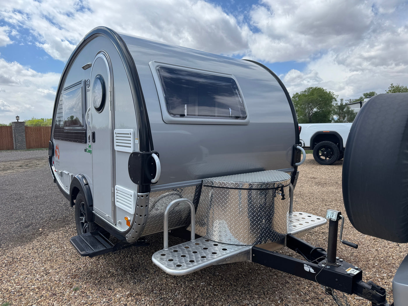 Modern grey teardrop RV rental, parked on gravel with a diamond plate storage box and steps. — photo 3