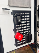 RV rental interior showing a black MOLLE panel with a first aid kit and other pouches for organized gear storage.