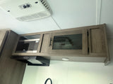 RV rental kitchen with modern overhead cabinets, built-in microwave, and range hood. An AC unit is on the ceiling.
