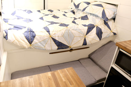 RV rental: Compact interior with comfy bed, adaptable seating, and built-in microwave.