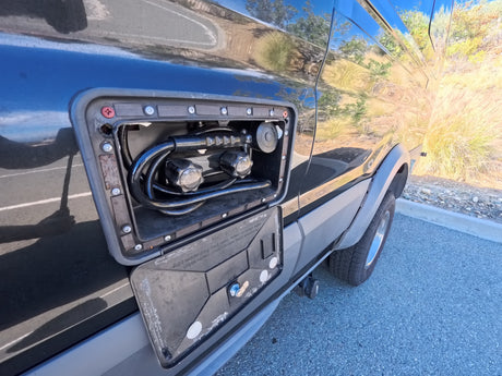 RV rental: Open utility panel shows outdoor shower with hot/cold knobs & winterize instructions for the water system.