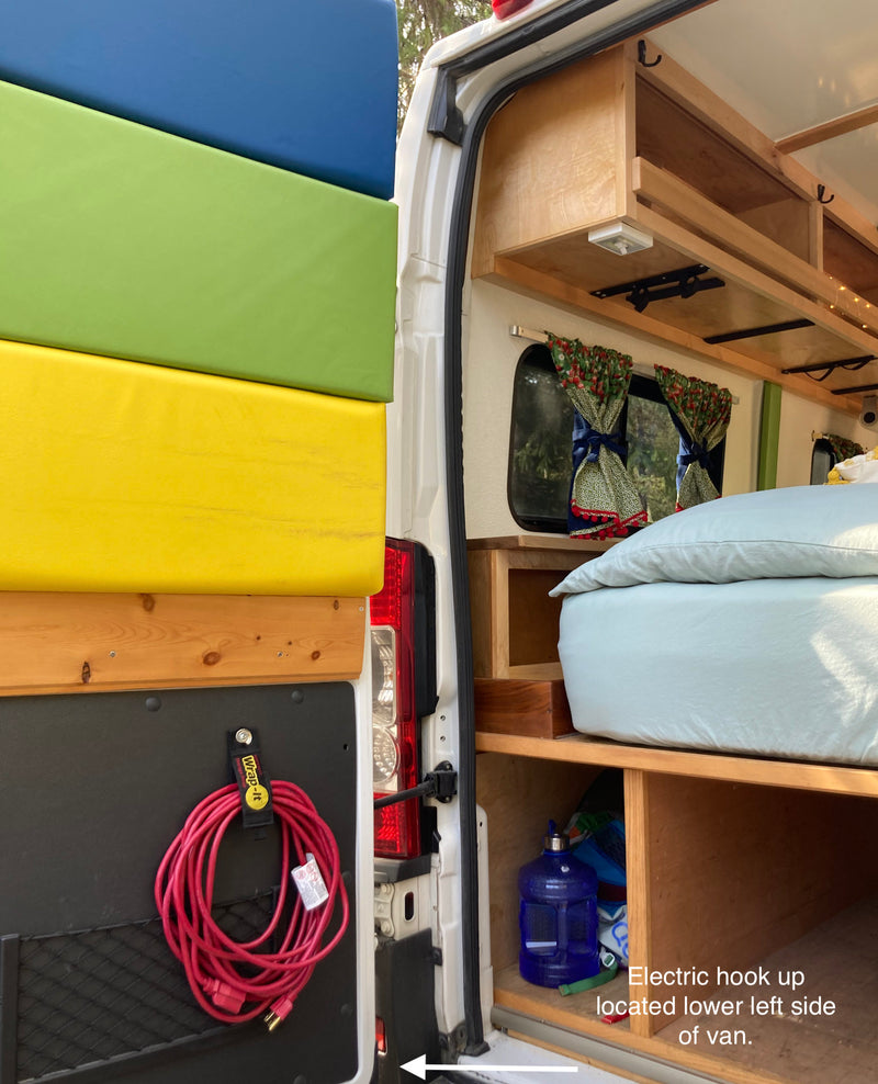 RV rental features: colorful cushions, interior storage, bed, and exterior power cord for hookup are visible inside a campervan. — photo 6