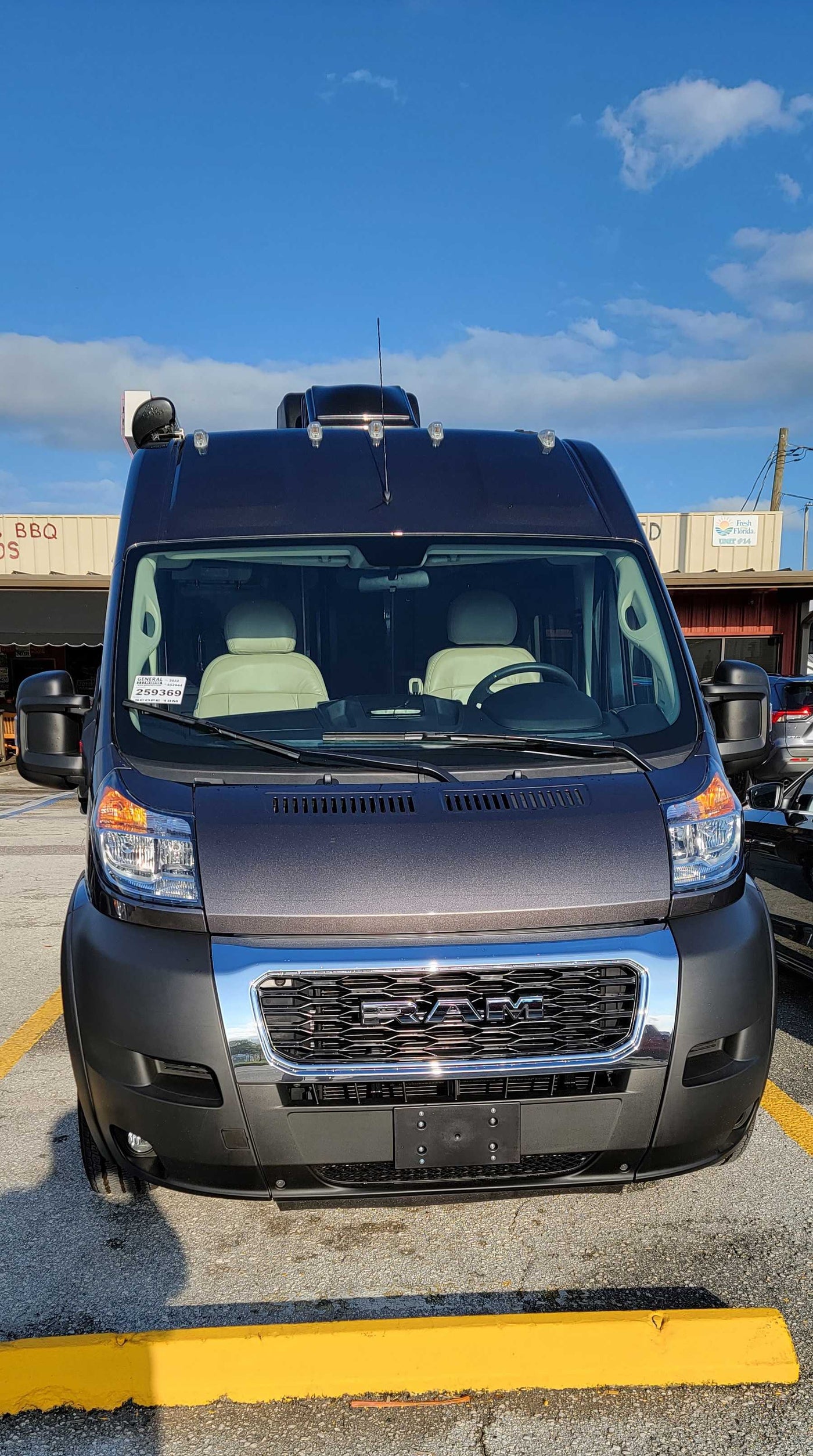 Front view of a dark gray Ram ProMaster camper van, perfect for an RV rental adventure. It's parked in a sunny lot. — photo 14
