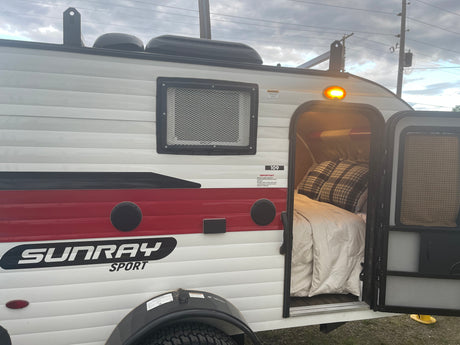 Compact Sunray Sport RV rental with open door showing cozy bed. Ready for your next outdoor adventure.