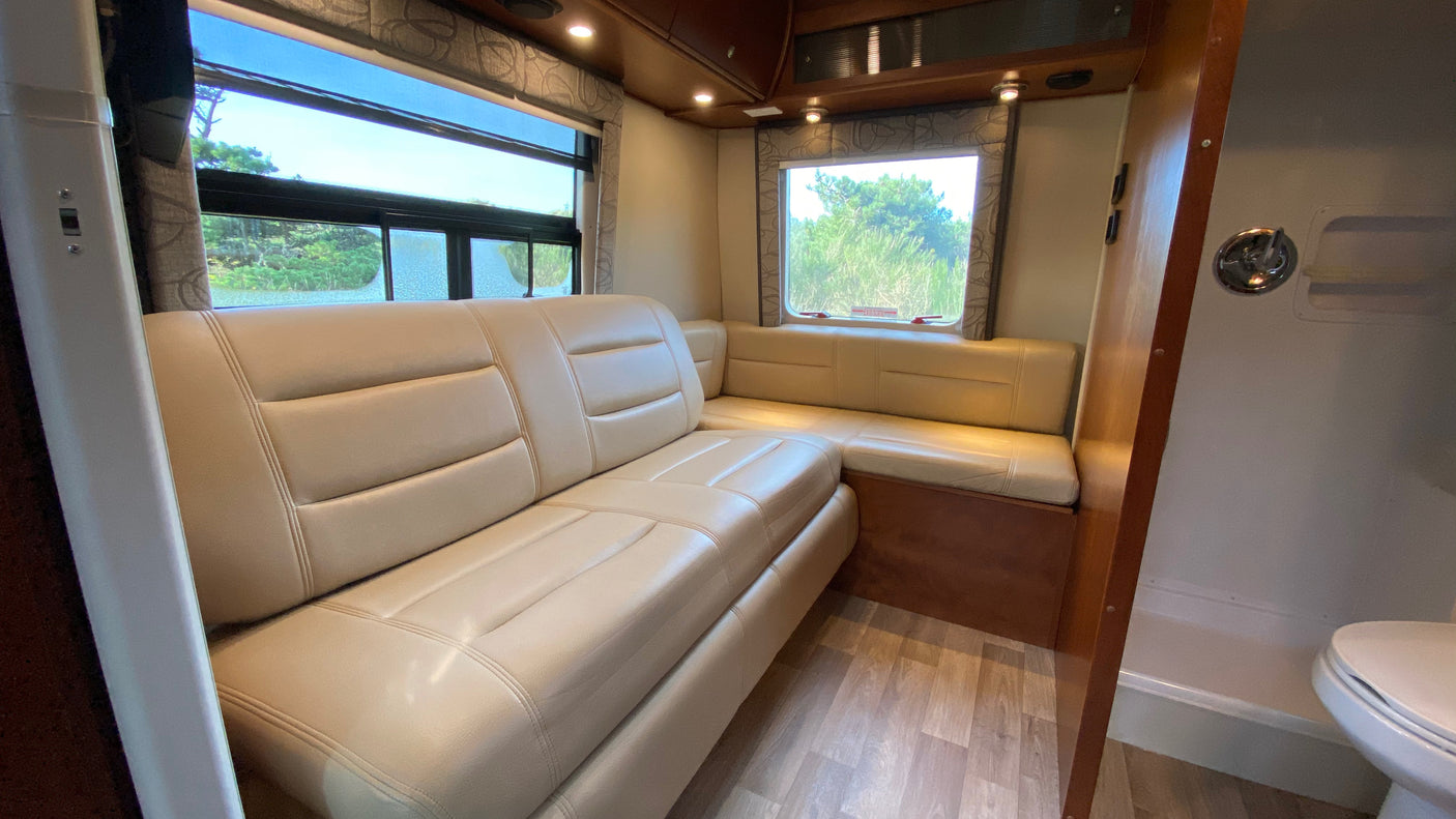 RV rental interior: A cozy, modern living space with light leather L-shaped seating and windows, ideal for travel.