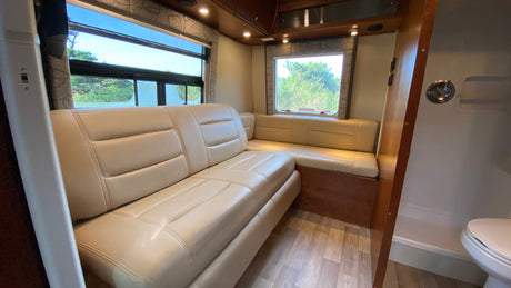 RV rental interior: A cozy, modern living space with light leather L-shaped seating and windows, ideal for travel.