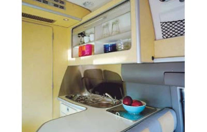 Explore this RV rental's efficient galley kitchen. Features include a sink, stovetop, and overhead cabinets with bright tableware. — photo 3