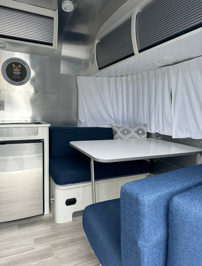  and privacy curtains.|An RV rental interior showing a dinette with blue benches