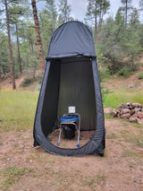 Black camping privacy tent houses a blue portable toilet with paper, ideal for RV rental trips.