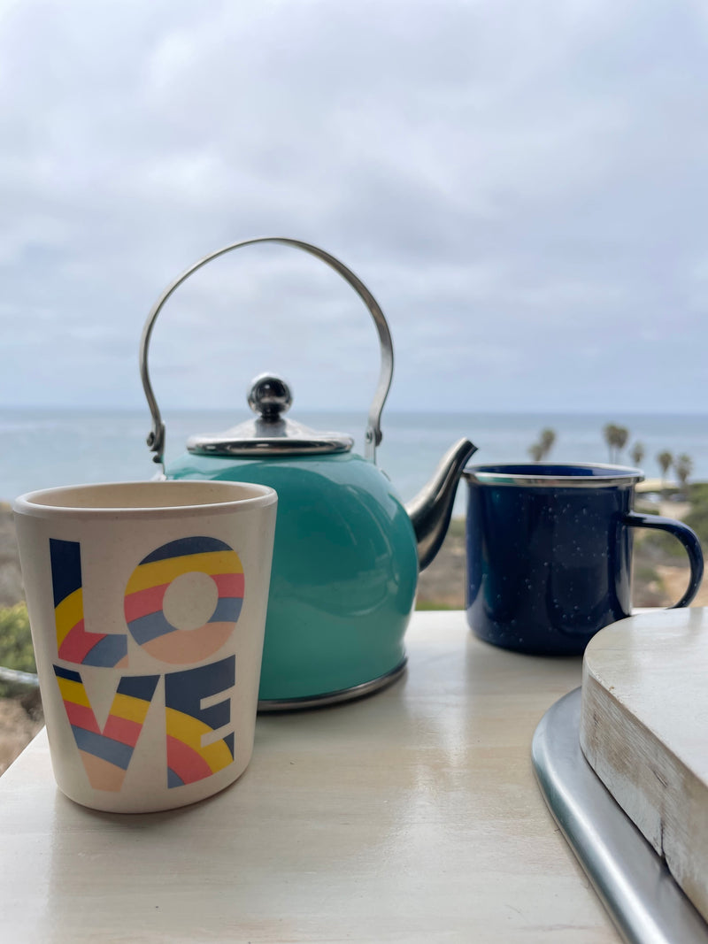 Enjoying a serene ocean view from an RV rental with a turquoise kettle and two mugs, one with "LOVE" and a blue enamel. — photo 15