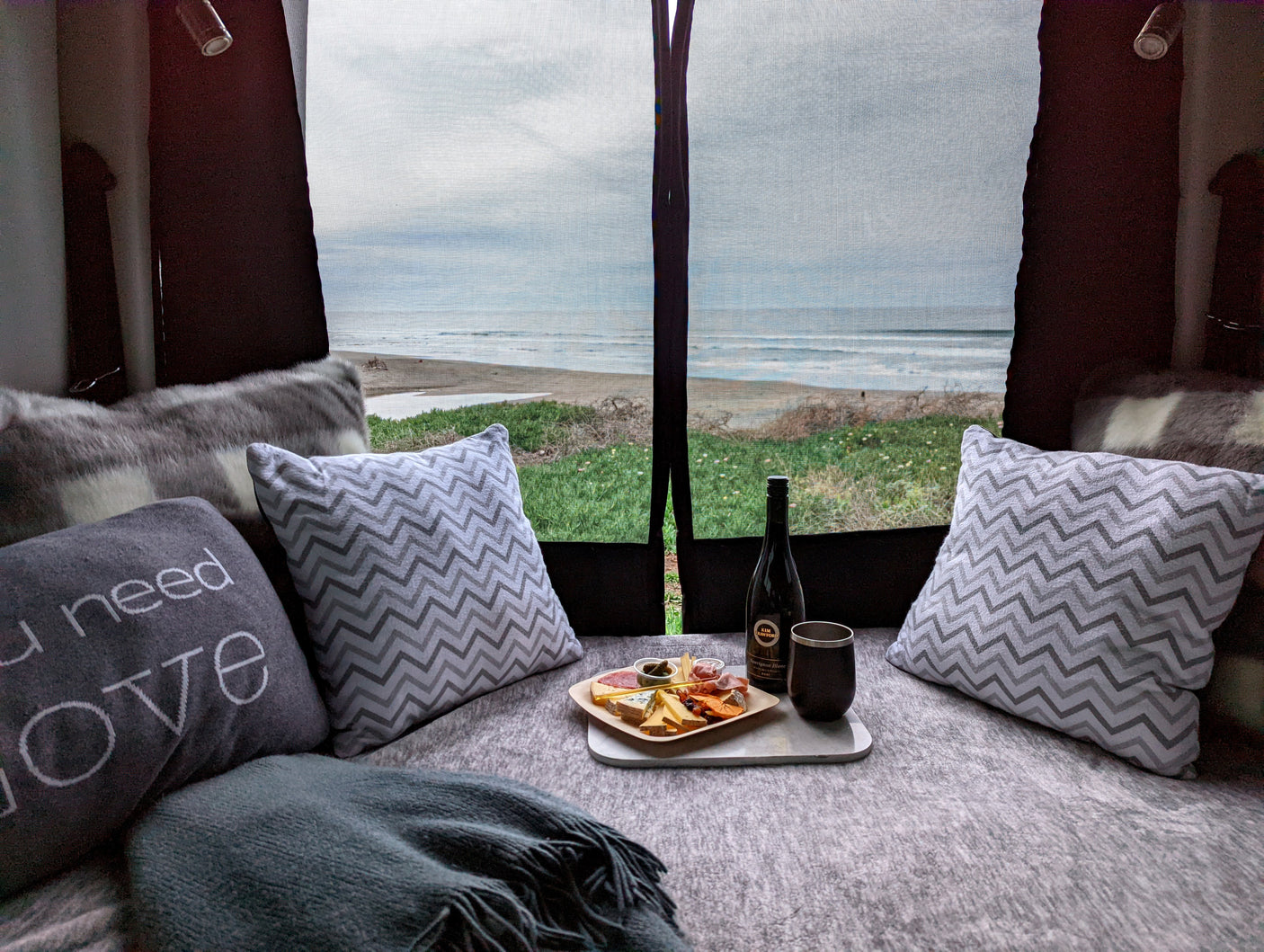 Cozy RV rental with ocean view: wine, charcuterie board, and plush pillows make for a perfect beachside retreat.