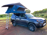 Dark gray SUV with rooftop tent & ladder, ideal for rv rental adventures on dirt road.