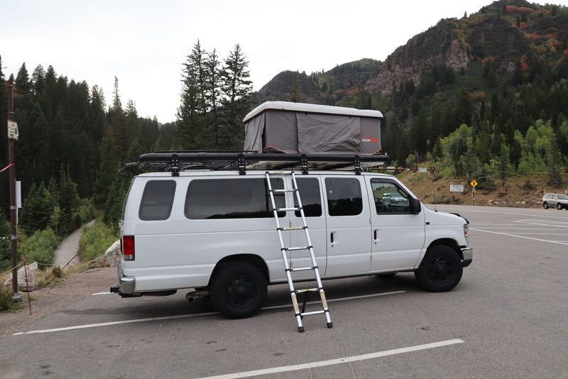 White camper van with a rooftop tent and ladder, parked in a scenic mountain lot. Perfect for an rv rental adventure! — photo 6