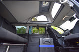 Rv rental camper van interior with pop-top roof open, showing a convertible bed, portable fridge, and fans for comfortable travel.