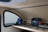 RV rental camper interior features Jackery portable power, coffee, and cooking stove on a shelf, with clever bungee storage.