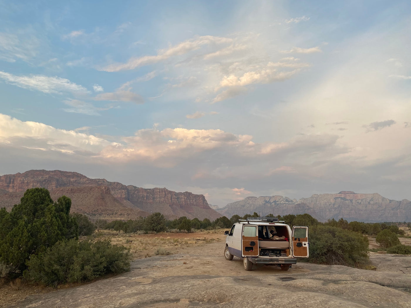 Your next adventure! This RV rental van is perfectly parked with doors open, showcasing a cozy setup among desert mountains. — photo 9