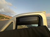RV rental: Inside view shows a custom vented window framing scenic mountains, the road, and ocean waves.