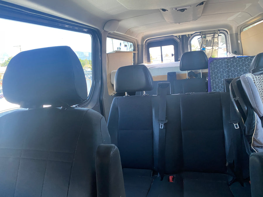 Cozy RV rental interior: view from front seats showing spacious rear seating and a neatly set up bed area.
