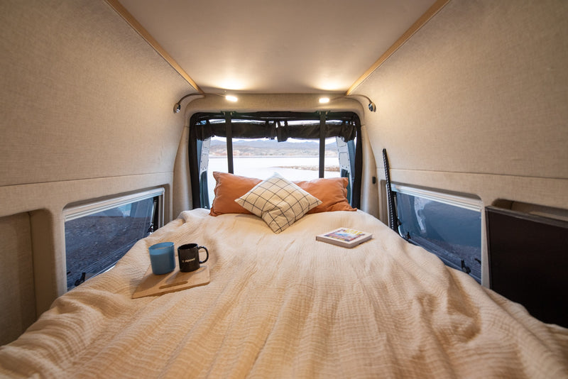 Wake up to stunning views in this cozy rv rental. Comfortable bed inside a camper van, overlooking a scenic lake. — photo 12