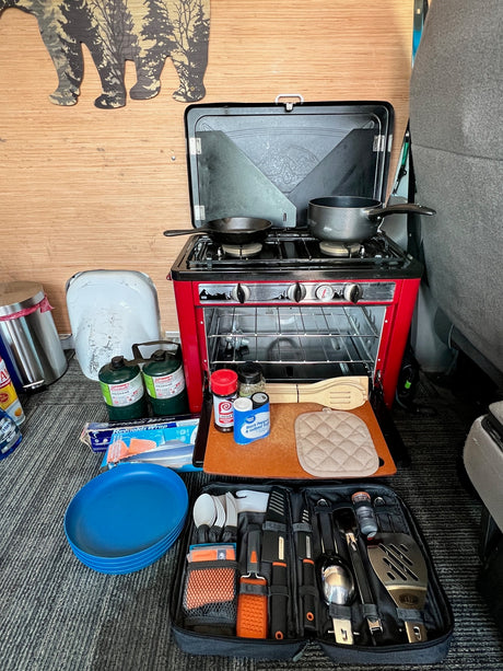RV rental compact kitchen setup: portable stove/oven, cooking tools, and supplies for camping meals.