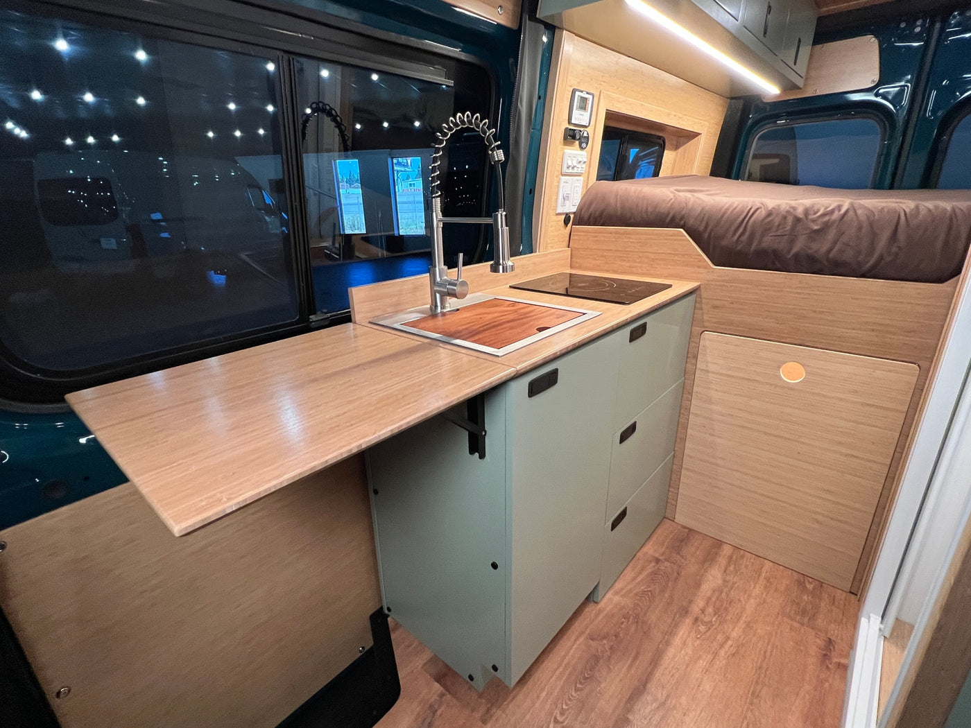  and bench with storage in wood and green tones.|RV rental interior: A light green fridge/seat with a Lagun table — photo 6