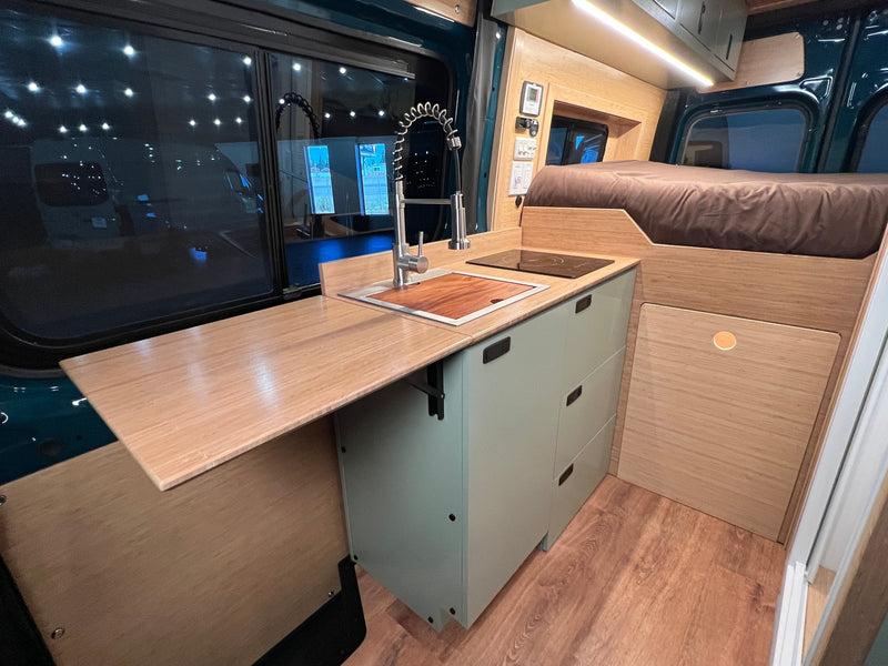  and bench with storage in wood and green tones.|RV rental interior: A light green fridge/seat with a Lagun table — photo 6