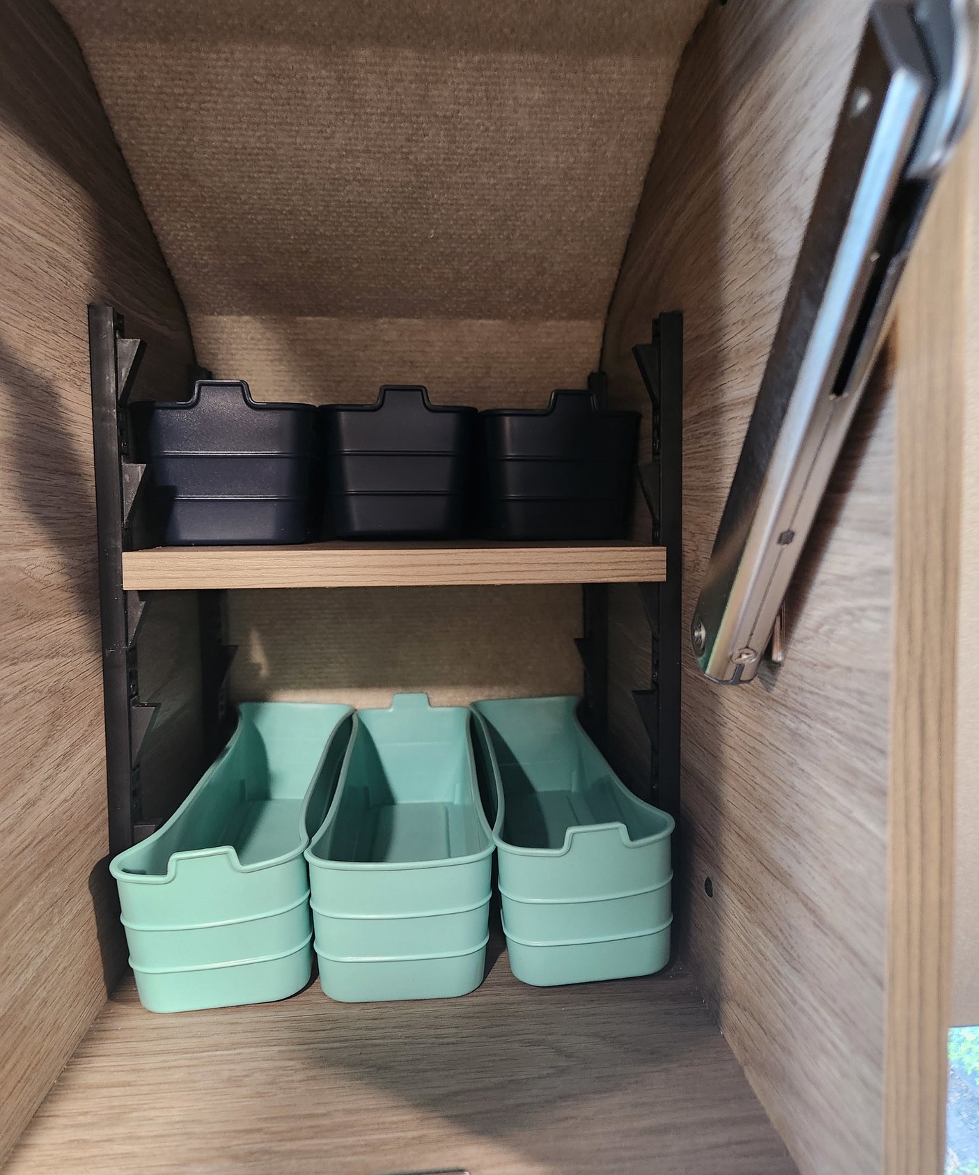 RV rental interior shows clever storage: black and mint green bins on shelves, perfect for maximizing compact space.