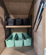 RV rental interior shows clever storage: black and mint green bins on shelves, perfect for maximizing compact space.