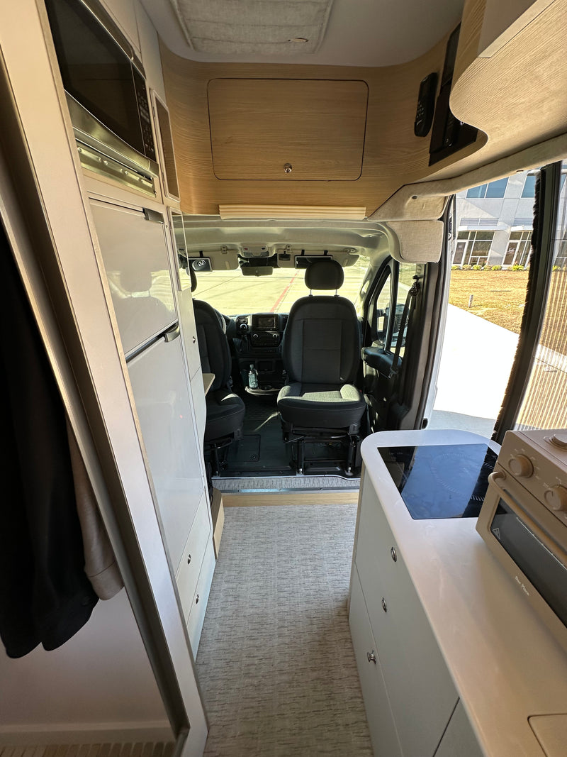 Stylish rv rental interior showing a modern kitchenette with cooktop, microwave, and front driver's area. — photo 8
