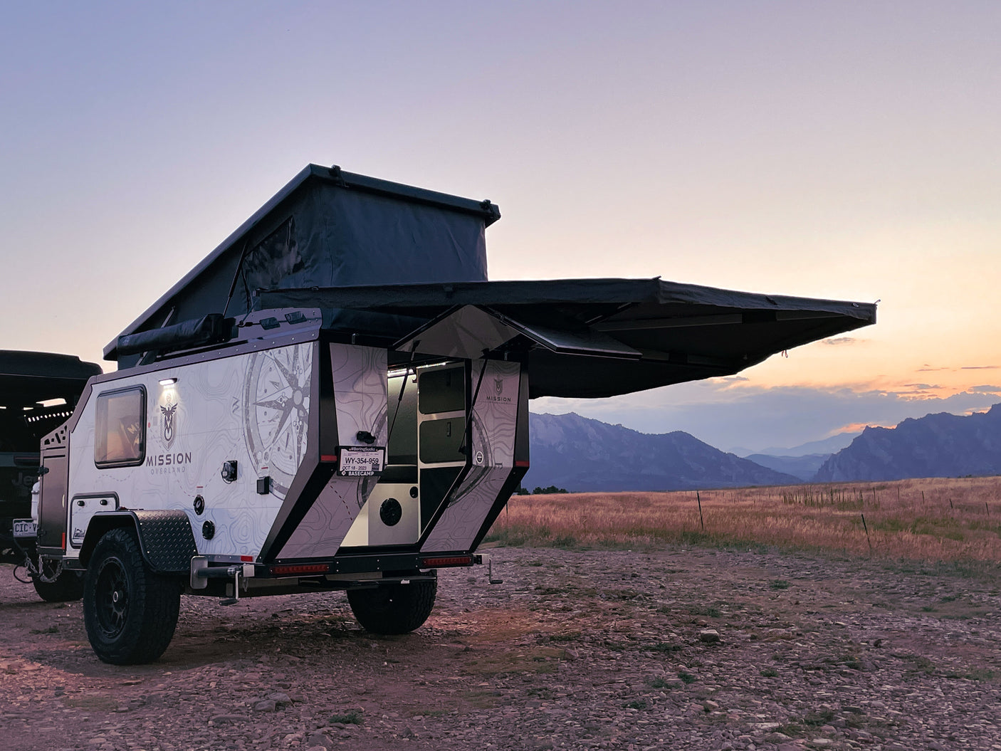 Overland RV rental with open kitchen & rooftop tent, ready for adventure at sunset in the mountains.