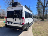 White Thor Sequence RV rental, equipped with a bike rack and roof AC unit, parked on a paved driveway on a sunny day.