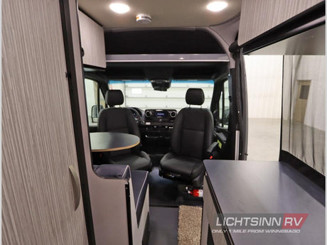 Inside this RV rental, the front cabin features swivel seats, a dining table, and compact living area.