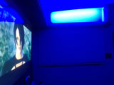 RV rental interior with striking blue ambient lighting, a screen showing a video game, and horizontal window blinds.