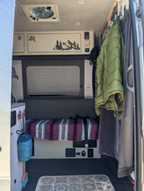 Inside a compact RV rental: bench seating, customized cabinets, and hanging storage for a comfy journey.