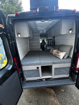 Interior of an RV rental camper van: a cozy bed, kitchen, and overhead storage for your travel needs.