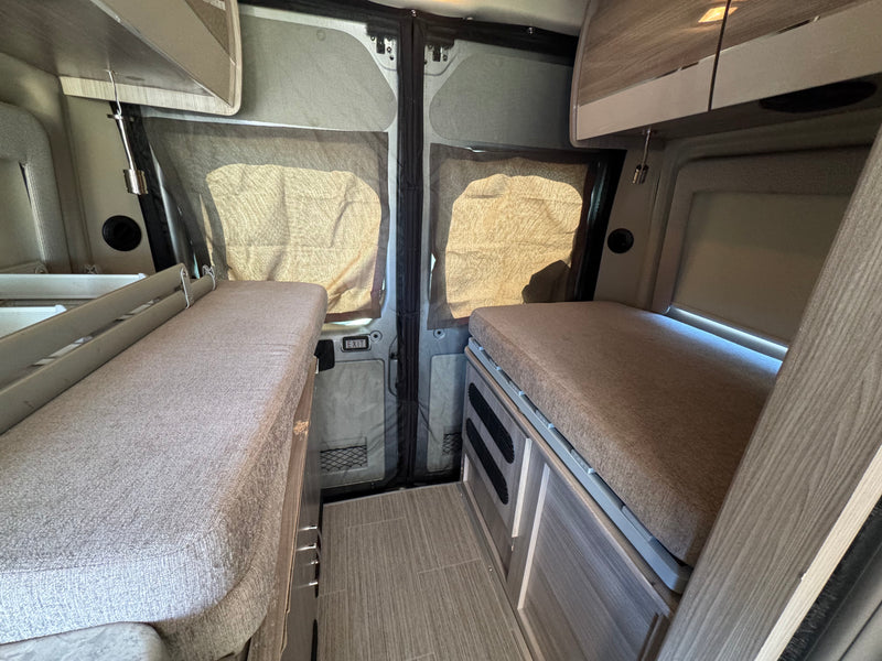 RV rental interior: Twin beds, central aisle, and screened back doors create a cozy camper van sleeping area. — photo 8