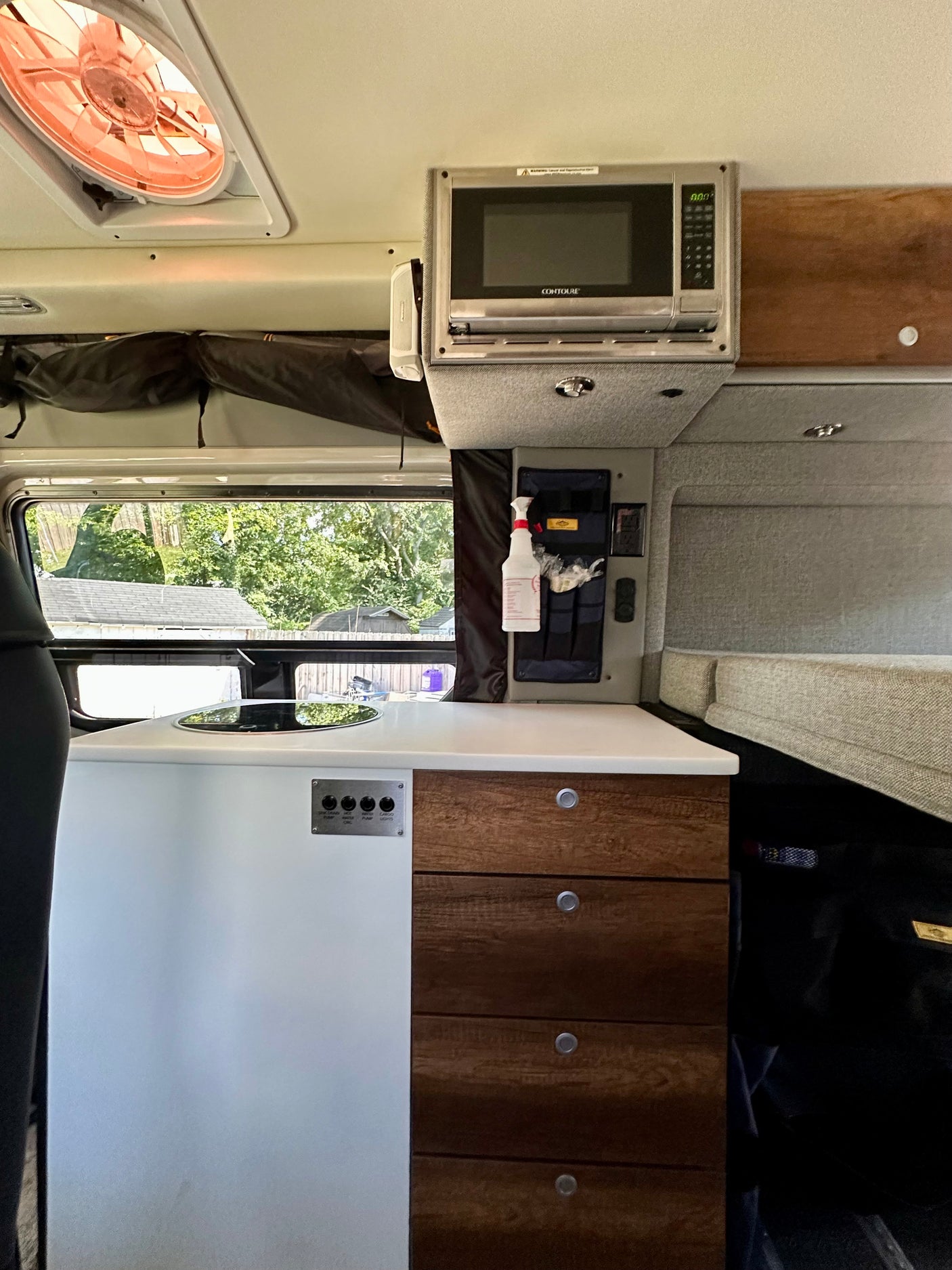 Inside a modern RV rental, find a well-equipped kitchen area, microwave, and organized storage for your journey.