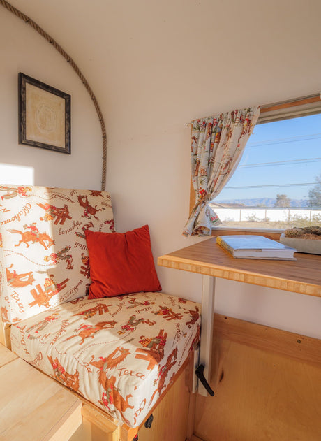 Charming RV rental interior with western-print cushions, a table, and a desert view through the window.